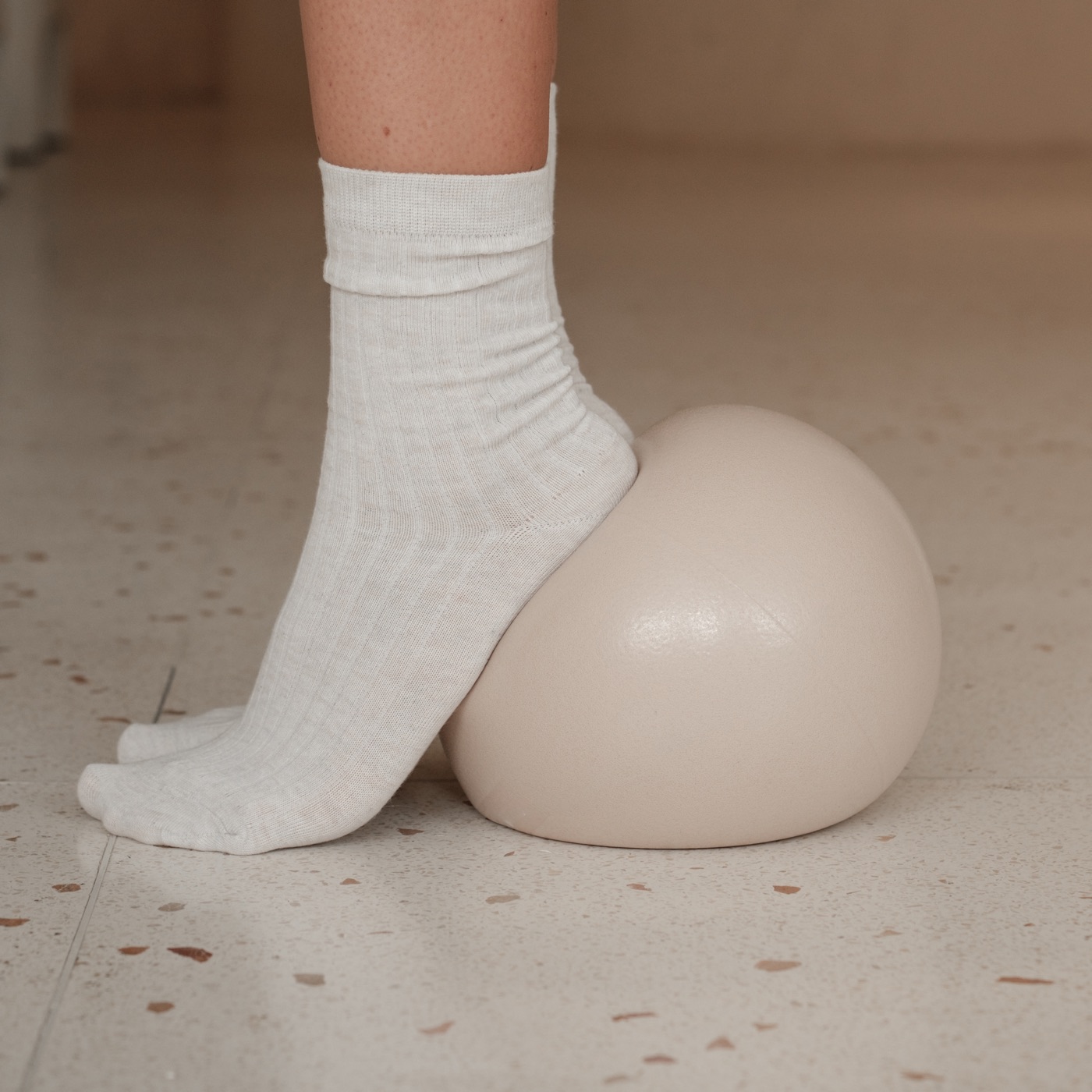 Pied posé sur une balle de pilates crème